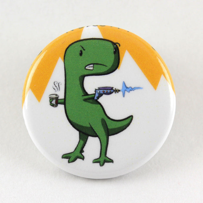 A button pin feature a stern looking T-Rex holding a latté in one hand and a laser gun in the other