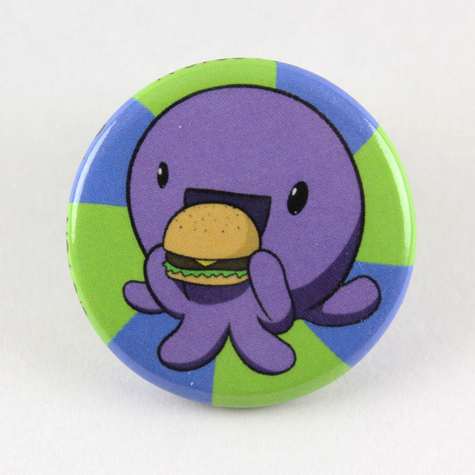 A button pin showing a rather gregarious octopus biting into a massive burger.  Don't eat the pin